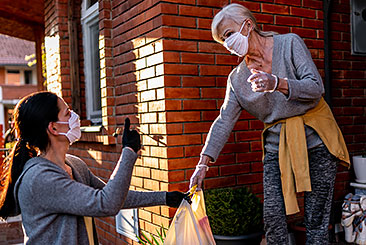 volunteer passing groceries to a mature woman volunteer passing groceries to a mature woman